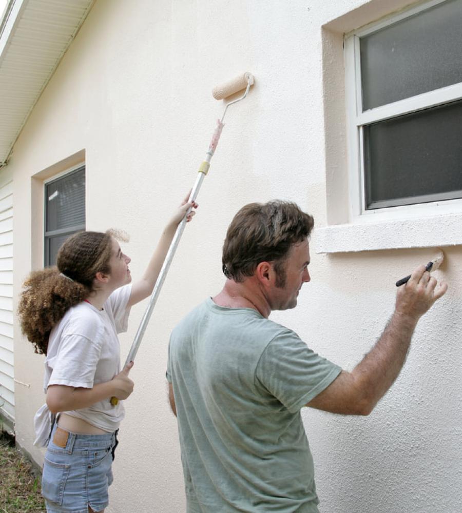 people painting a stucco house